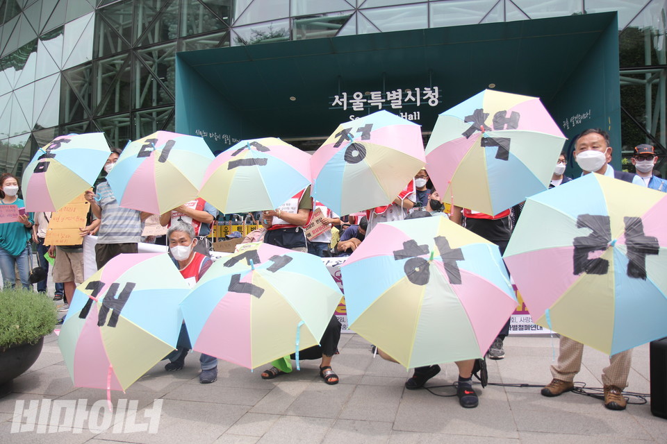 기자회견 참가자들이 우산을 펼쳐 보이는 퍼포먼스를 하고 있다. “홈리스 정책 개선하라”는 문구가 우산들에 한 글자씩 적혀 있다. 사진 이슬하