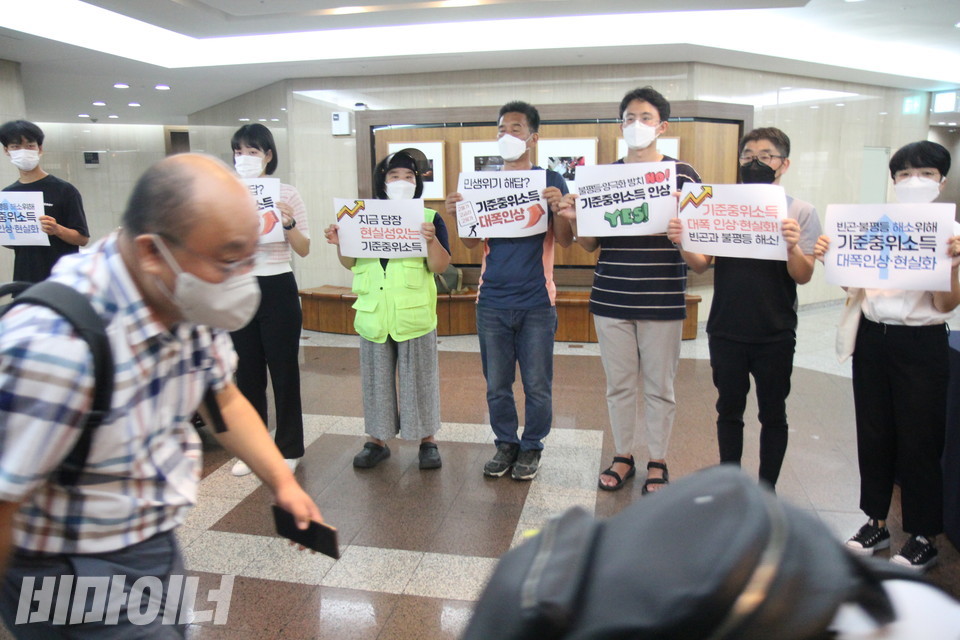 피케팅 중인 활동가들 앞으로 위원들이 몸을 숙인 채 황급히 회의장으로 들어서고 있다. 사진 이슬하
