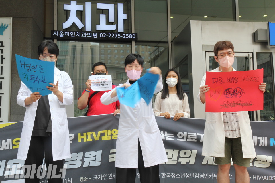 의사 가운을 입은 기자회견 참가자들이 연세오케이병원 측에서 했다고 알려진 말들이 적힌 피켓을 찢는 퍼포먼스를 하고 있다. 피켓에는 각각 “HIV 감염인을 치료할 특수한 장비가 없습니다”, “에이즈 환자가 있다는 소문이 나면 병원이 어려워집니다”, “다른 병원 구해오면 내가 무료 봉사로 수술해줄게요”라고 적혀 있다. 사진 이슬하