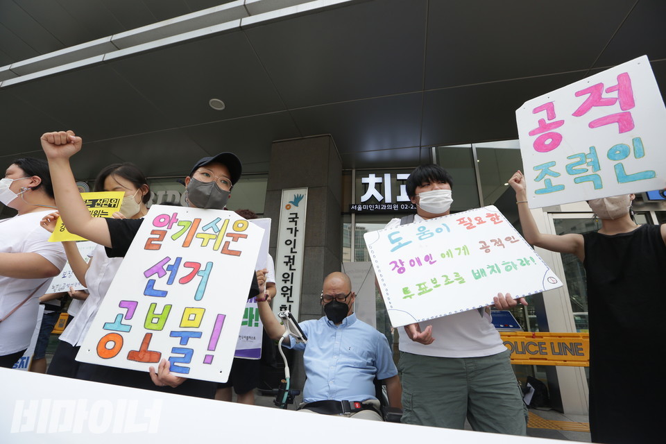 기자회견 참가자들이 투쟁을 외치고 있다. 이들은 “알기 쉬운 선거 공보물!” “도움이 필요한 장애인에게 공적인 투표보조를 배치하라” “공적 조력인”이라고 적힌 손피켓을 들고 있다. 사진 강혜민 