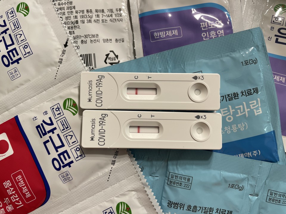 몸살감기, 두통, 기침, 인후통 등과 관련한 약 봉투 위에 코로나 자가진단키트가 있다. 자가진단키트에는 C에만 빨간색 한 줄(음성)이 나 있다. 사진 안희제 