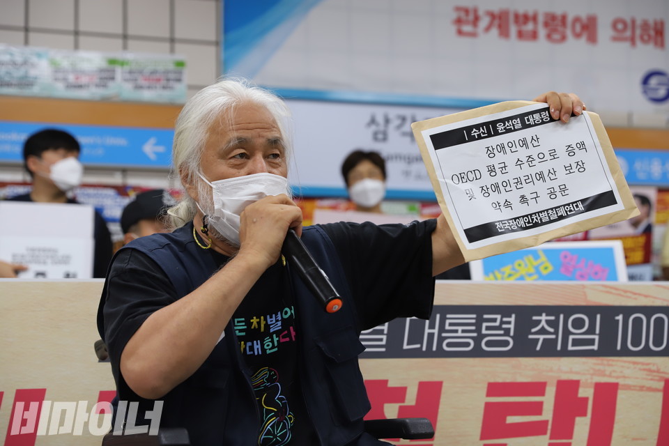 박경석 전국장애인차별철폐연대 상임공동대표가 삭발식에 앞서 발언하고 있다. 그가 들어 보인 봉투에는 “수신 윤석열 대통령 / 장애인예산 OECD 평균 수준으로 증액 및 장애인권리예산 보장 약속 촉구 공문 / 전국장애인차별철폐연대”라고 적혀있다. 사진 이슬하