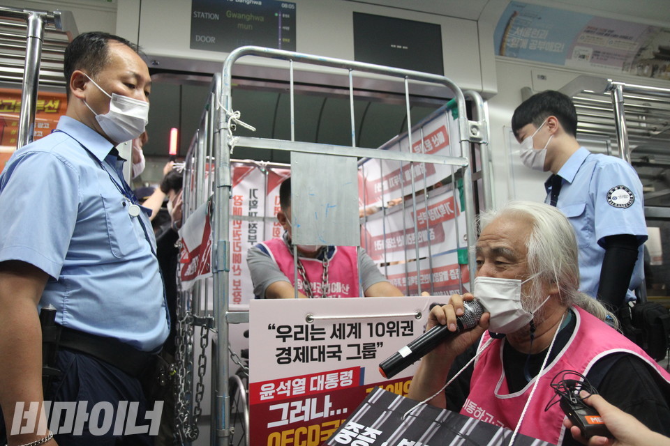 지난 1일 광화문역에서 지하철에 탄 박경석 대표가 발언하고 있다. 그의 옆으로 철창 수레 안에 자신을 가둔 권달주 전장연 상임공동대표의 모습이 보인다. 사진 이슬하