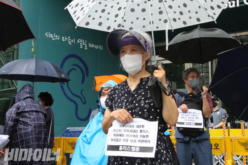 기자회견 참가자가 “코로나19의 재유행 여전히 사각지대인 홈리스, 지자체는 자가격리 가능한 주거공간 지금 당장 마련하라”고 적힌 피켓을 들고 있다. 사진 이슬하
