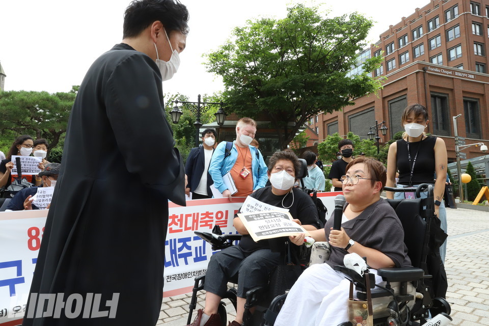 박김영희 장애인차별금지추진연대 상임대표와 이형숙 서울시장애인자립생활센터협의회 회장이 이길재 명동성당 수석부주임 신부에게 면담 요청서를 전달하고 있다. 사진 이슬하