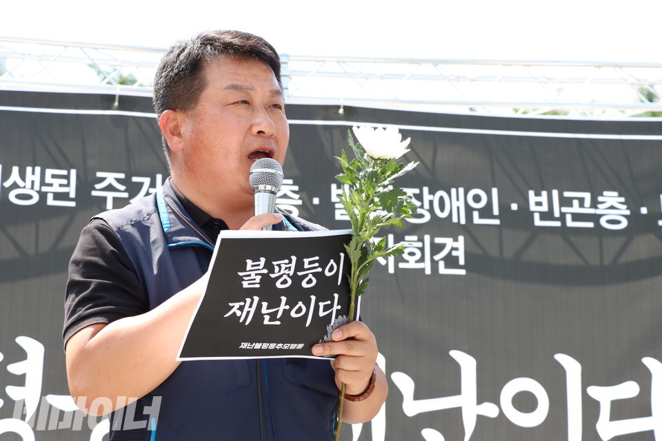 강규혁 민주노총 서비스연맹 위원장이 발언하고 있다. 손에는 “불평등은 재난이다”라고 적힌 피켓과 함께 하얀 국화를 들었다. 사진 강혜민