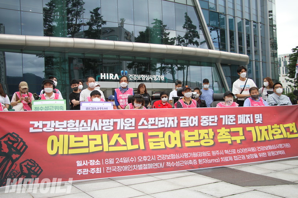 ‘척수성근위축증 환자 의약품 접근권 보장을 위한 공동대책위원회’는 24일 오후 2시 강원도 원주에 있는 건강보험심사평가원 앞에서 기자회견을 열었다. 기자회견 참가자들 앞에 놓인 현수막에 “건강보험심사평가원 스핀라자 급여 중단 기준 폐지 및 에브리스디 급여 보장 촉구 기자회견”이라고 적혀있다. 사진 이슬하