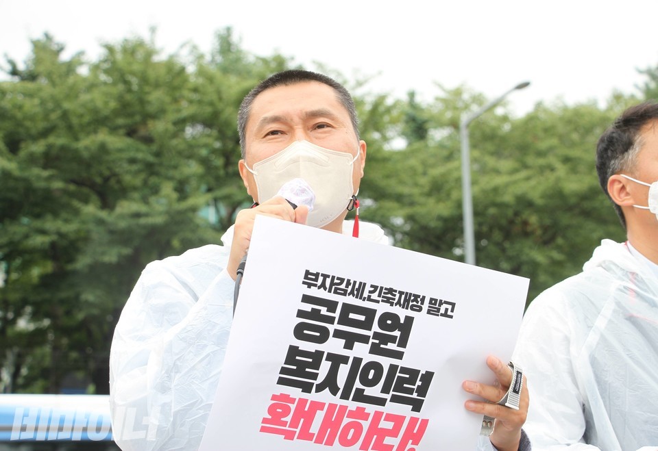 전호일 전국공무원노동조합 위원장이 기자회견에서 발언하고 있다. 손에 쥔 피켓에는 “부자 감세, 긴축재정 말고 공무원 복지 인력 확대하라!”고 적혀있다. 사진 이슬하