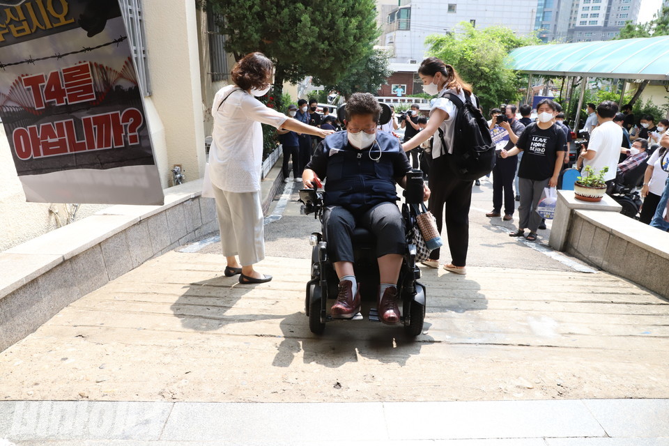 지난달 19일, 이형숙 회장은 용산서에 자진출석 했다가 엘리베이터가 없어 조사를 거부했다. 이 회장이 용산서 정문 앞 경사가 험해서 뒤로 내려가고 있다. 다른 활동가 두 명이 이 회장의 휠체어를 받치고 있다. 이 사진은 모의재판에서 증거로 제출됐다. 사진 하민지