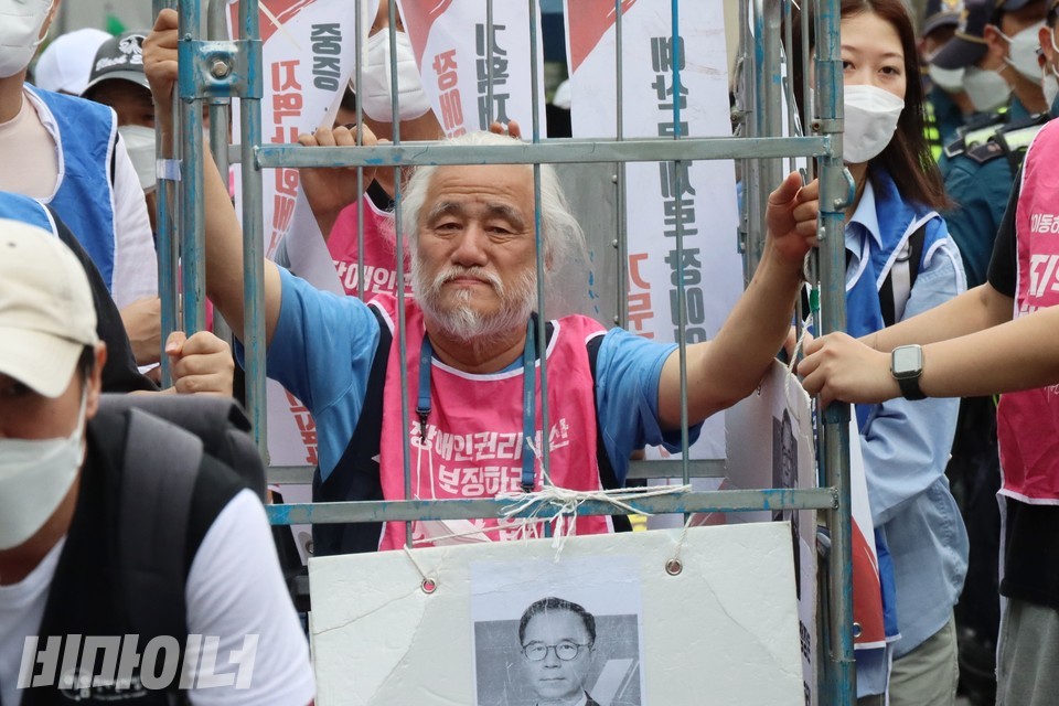 전국장애인차별철폐연대 활동가들이 청와대까지 행진하고 있다. 박경석 전장연 상임공동대표가 철창 속에서 행진하며 생각에 잠긴 표정을 짓고 있다. 사진 하민지