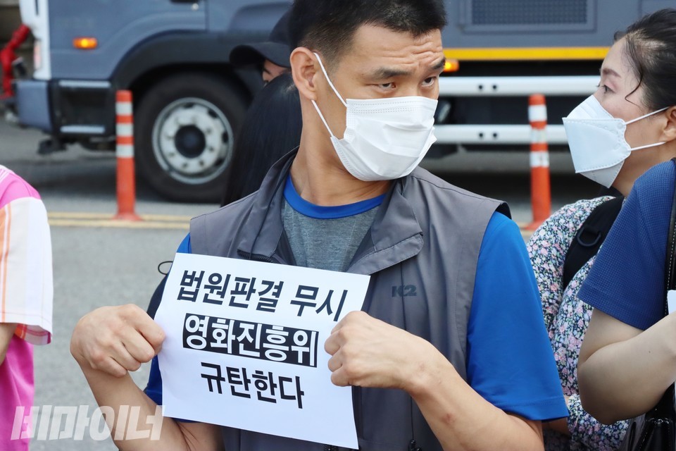 한 활동가가 ‘법원판결 무시, 영화진흥위 규탄한다’라는 피켓을 들고 있다. 사진 하민지