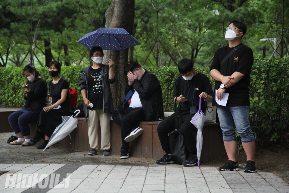 추모식에 참석한 사람들이 공원 한쪽에서 저마다의 방식으로 슬퍼하고 있다. 멍하니 하늘을 올려다보기도 하고, 무심하게 핸드폰만 내려다보기도 하고, 두 손으로 얼굴을 감싸 쥐기도 한다. 사진 이슬하