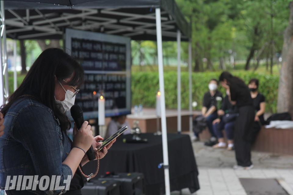 김혜미 피플퍼스트서울센터 활동가가 준비해온 편지를 추모식에서 읽고 있다. 멀리, 두 손으로 얼굴을 감싼 채 울고 있는 김하은 피플퍼스트성북센터 활동가가 흐릿하게 보인다. 사진 이슬하