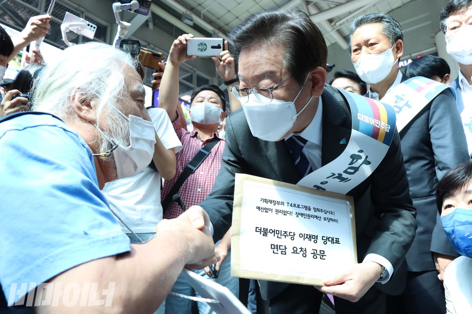 박경석 전장연 대표가 용산역에서 이재명 더불어민주당 당대표를 만나 장애인권리예산에 대한 국회 책임을 당부하고 있다. 이 당대표 손에는 ‘더불어민주당 이재명 당대표 면담 요청 공문’이 들려 있다. 사진 강혜민 