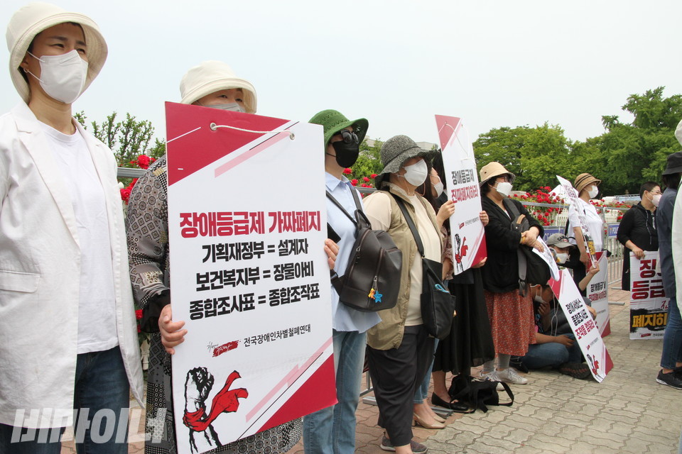 지난 5월 19일, 종합조사의 문제점을 규탄하는 기자회견 현장. 기자회견 참가자가 ‘장애등급제 가짜폐지, 기획재정부=설계자, 보건복지부=장물아비, 종합조사표=종합조작표’라는 팻말을 들고 있다. 사진 비마이너DB