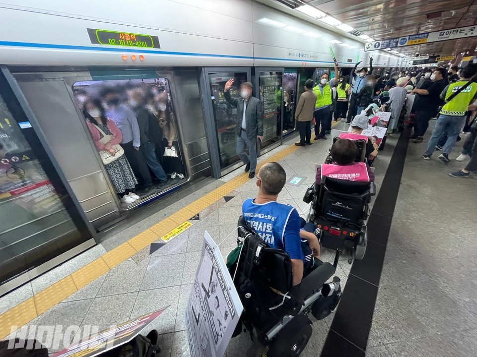 장애인 활동가들이 서울역에서 내려 줄지어 있다. 열차는 휠체어를 이용하지 않는 시민으로 꽉 차 있다. 사진 하민지 