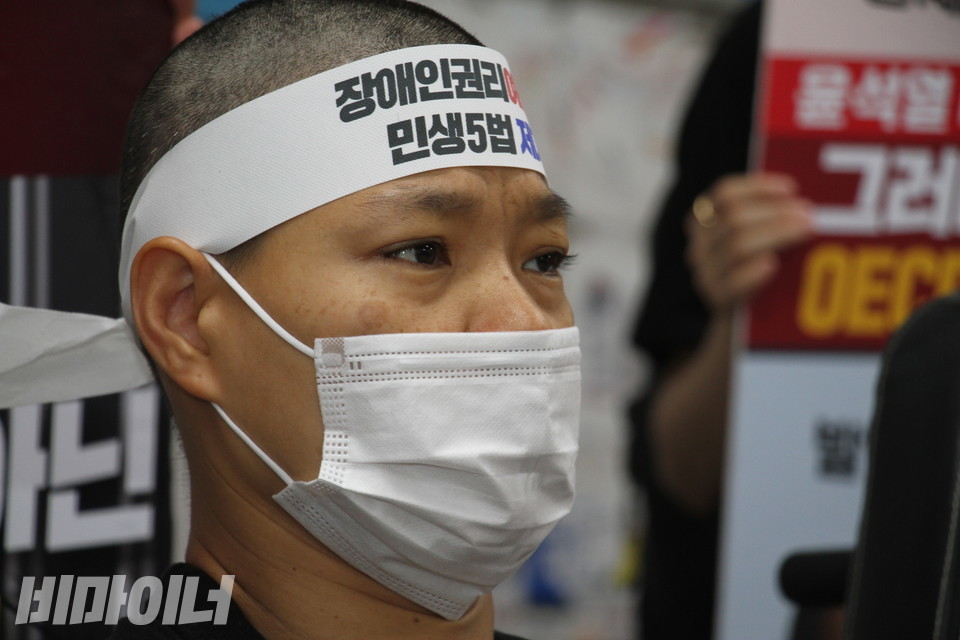 삭발을 마친 서지원 활동가가 머리에 ‘장애인권리, 민생5법’이라 적힌 띠를 둘렀다. 사진 이슬하