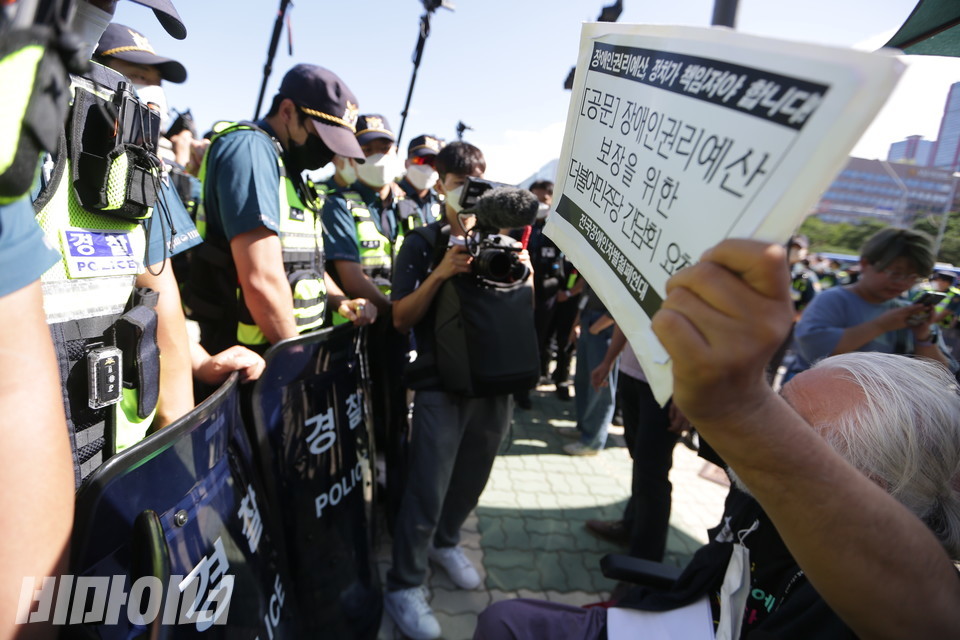 경찰에 의해 길이 막히자, 박경석 대표가 장애인권리예산 보장을 위한 간담회 요청 공문을 높이 들어 보이고 있다. 사진 강혜민