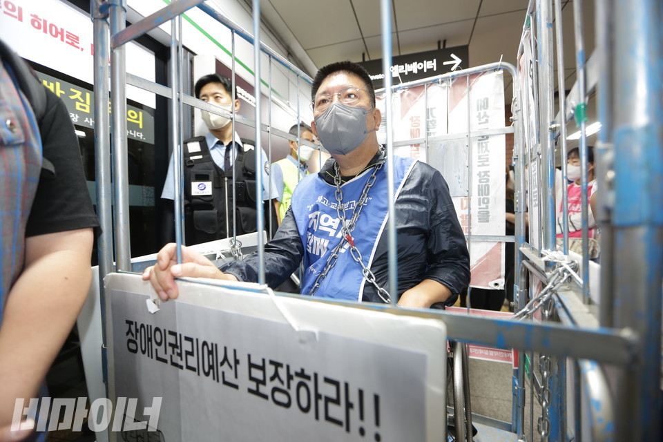 권달주 전장연 상임공동대표가 수용시설을 뜻하는 철창에 갇혀 이동하고 있다. 그의 목에는 쇠사슬이 매여 있다. 사진 강혜민