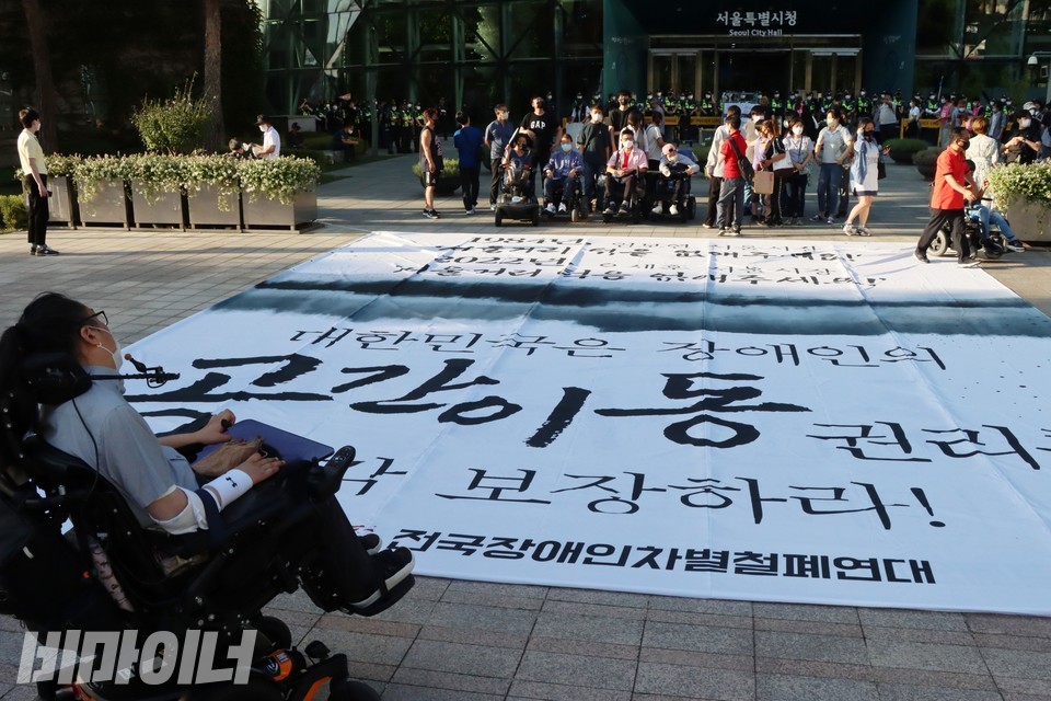 ‘대한민국은 장애인의 공간이동 권리를 즉각 보장하라’라고 적힌 커다란 현수막이 바닥에 놓여 있다. 