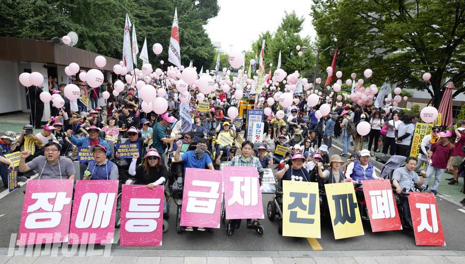 장애등급제 단계적 폐지가 시행되던 2019년 7월 1일, 전국장애인차별철폐연대가 장애등급제 ‘진짜’ 폐지를 요구하며 전동행진을 벌였다. 기획재정부 서울사무소(서울지방조달청) 앞에 모인 장애인 활동가들의 모습. 사진 비마이너 DB 