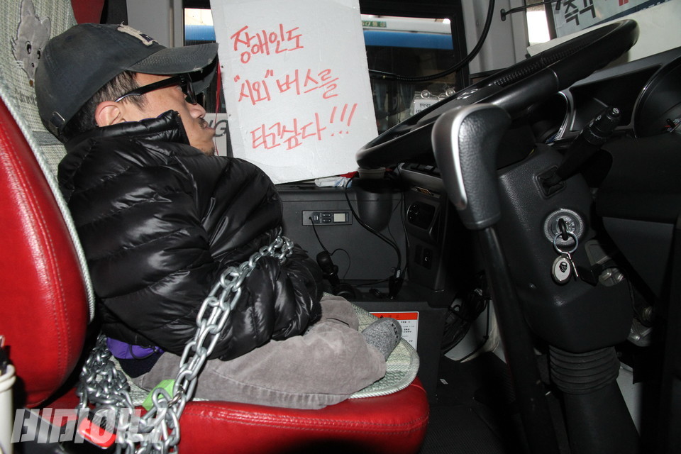 2014년 12월 1일, 고속버스터미널. 장애인 활동가가 부산행 시외버스 운전석에 앉아 쇠사슬로 자신의 몸을 묶은 채 앉아 있다. 그의 옆엔 “장애인도 시외버스를 타고 싶다”고 적힌 피켓이 있다. 사진 강혜민