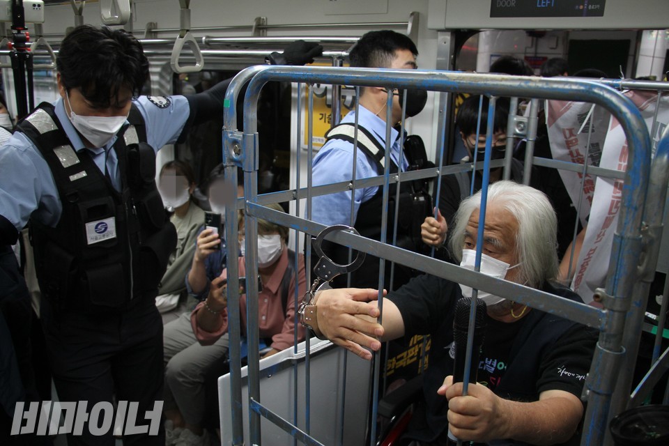 박경석 전장연 상임공동대표가 한 손을 수갑으로 철창에 묶은 채 지하철에 타고 있다. 사진 이슬하