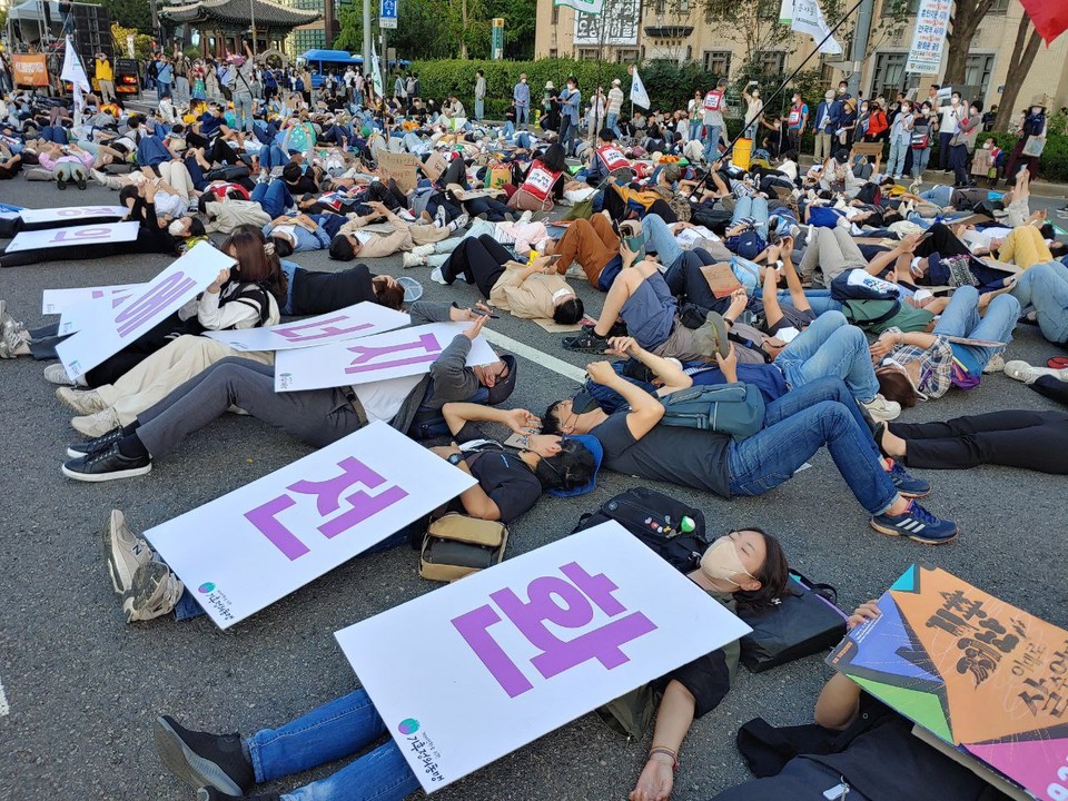 아스팔트 바닥에 누워 ‘다이-인(die-in)’ 시위를 하는 사람들. 다이-인 시위는 일정 시간 동안 죽은 듯 땅에 누워 있는 시위로 기후재난과 불평등 속에서 죽어가는 상황을 상징한다. 사진 구준모 