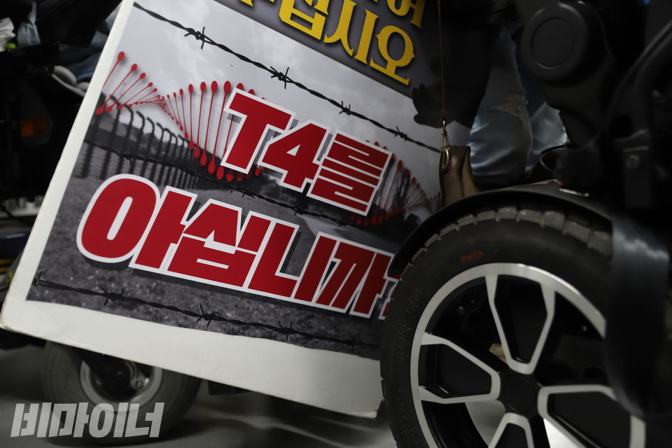 휠체어 바퀴 사이로 ‘T4를 아십니까’라는 문구가 적힌 피켓이 보인다. ‘T4(티포)’는 독일 베를린시에 있는 ‘티어가르텐 4번지’로, 1939년 이곳에서 독일 나치는 비용을 이유로 장애인 수십만 명을 집단으로 학살했다. 사진 복건우