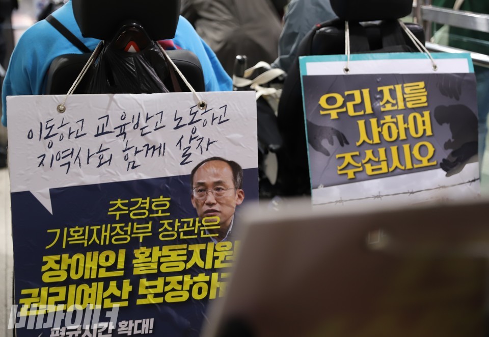 활동가들의 휠체어 뒤로 장애인권리예산 보장을 촉구하는 피켓들이 걸려 있다. 사진 복건우