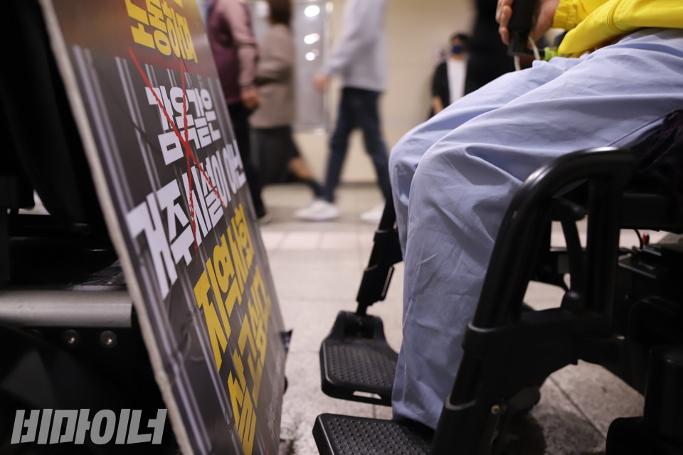 동대문역사문화공원역에서 4호선으로 환승하기 위해 엘리베이터를 기다리는 활동가들. 휠체어 너머로 역을 지나치는 승객들이 흐릿하게 보인다. 사진 복건우