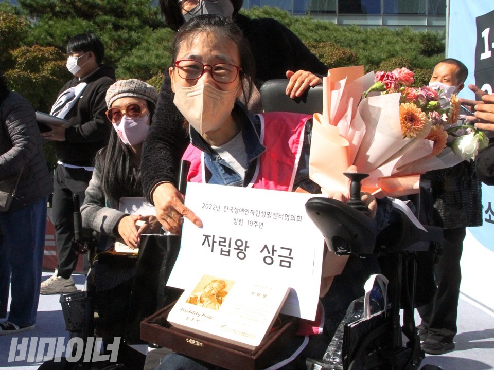 김보영 인천센터 활동가가 꽃다발, 상금, 상패를 들고 미소를 짓고 있다. 사진 하민지