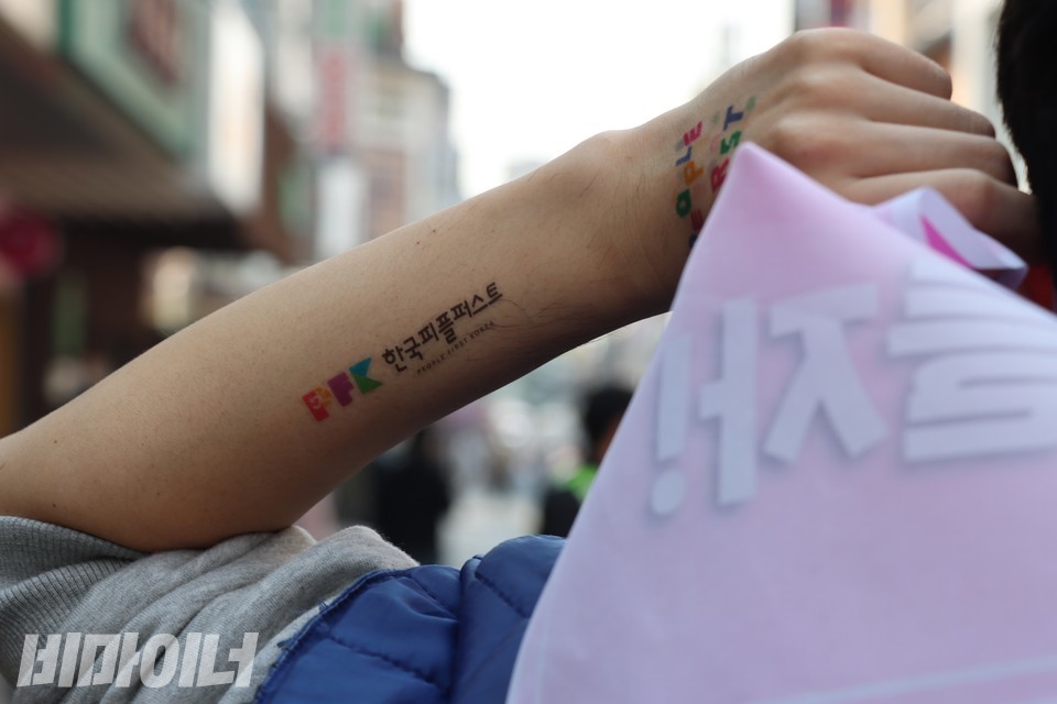 한 참가자가 왼팔에 한국피플퍼스트대회를 기념하는 타투 스티커를 붙이고 팻말을 든 채 행진 중이다. 사진 복건우