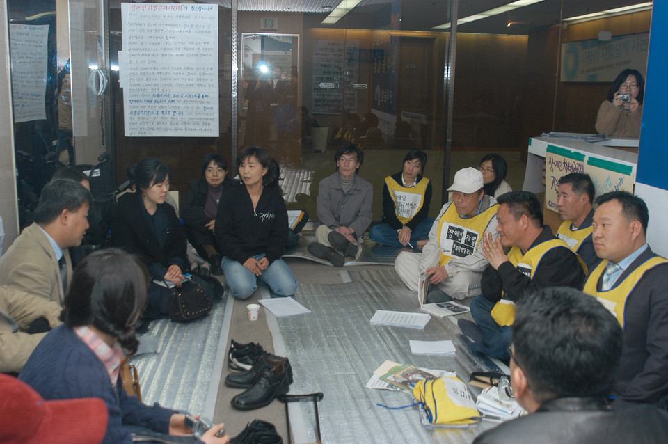 2006년 3월 31일, 장애인차별금지법제정을 요구하며 장애계가 국가인권위원회를 점거하고 단식농성을 하던 4일 차의 모습. 가운데 박옥순 활동가가 흰 글자로 ‘저항하라’고 적힌 검은 티를 입고 회의를 진행하고 있다. 사진 n_m