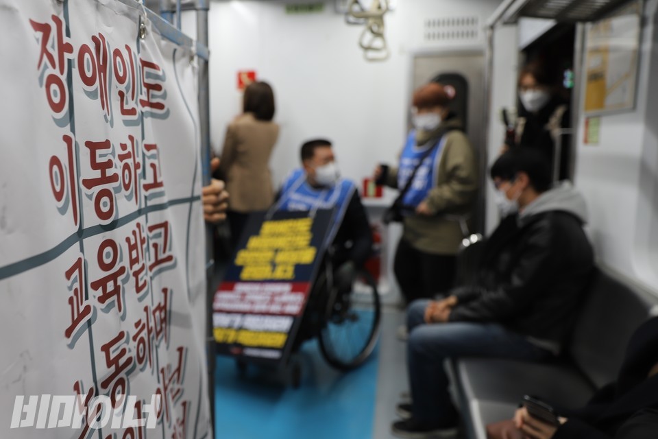 활동가들이 열차에 타고 있다. 왼쪽에 ‘장애인도 이동하고 교육받고 노동하며’라고 적힌 현수막이 보인다. 사진 하민지