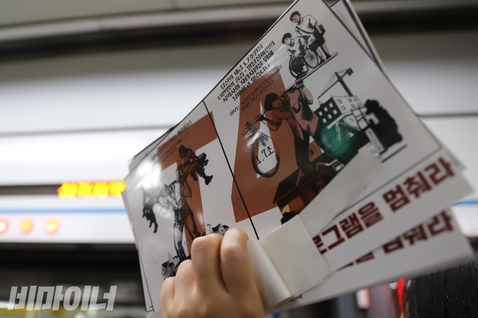 한 활동가가 스티커를 높이 들고 있다. 스티커에는 ‘당신의 세금 1.7조 원을 13만 명의 중증·발달장애인의 지역사회 자립지원을 위해 낭비하고 있습니다. 정부는 시설을 늘려서 당신의 짐을 줄여드리고 있습니다. T4 프로그램을 멈춰라’라고 적혀 있다. 사진 하민지