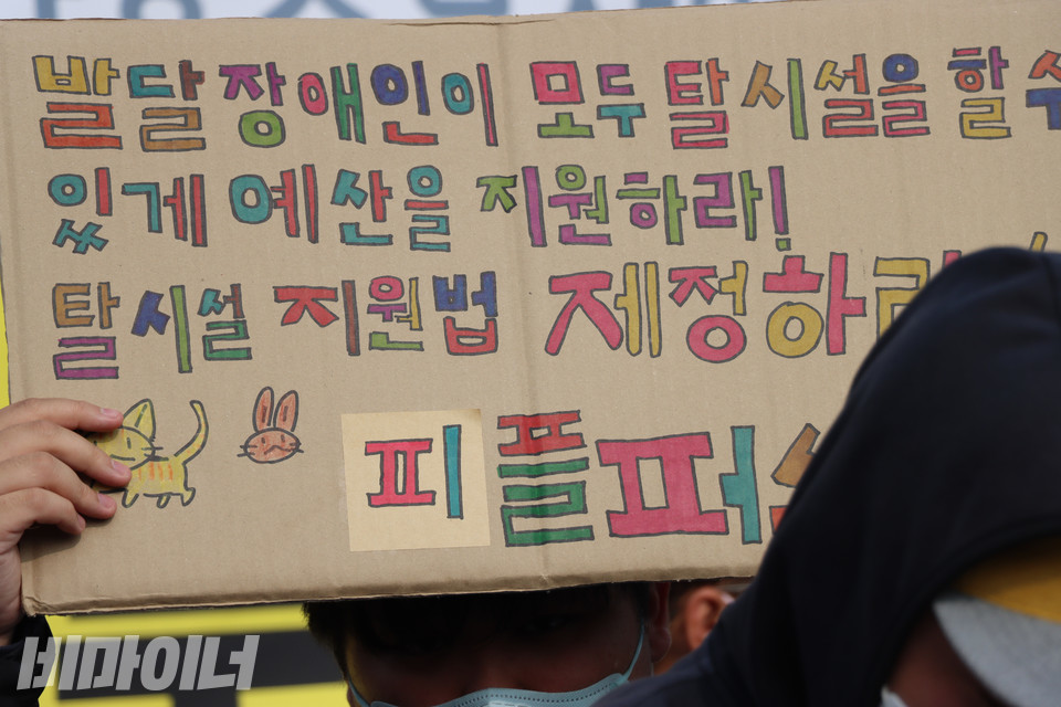 한 피플퍼스트서울센터 활동가가 탈시설지원법 제정을 촉구하는 손팻말을 들어 보이고 있다. 사진 복건우