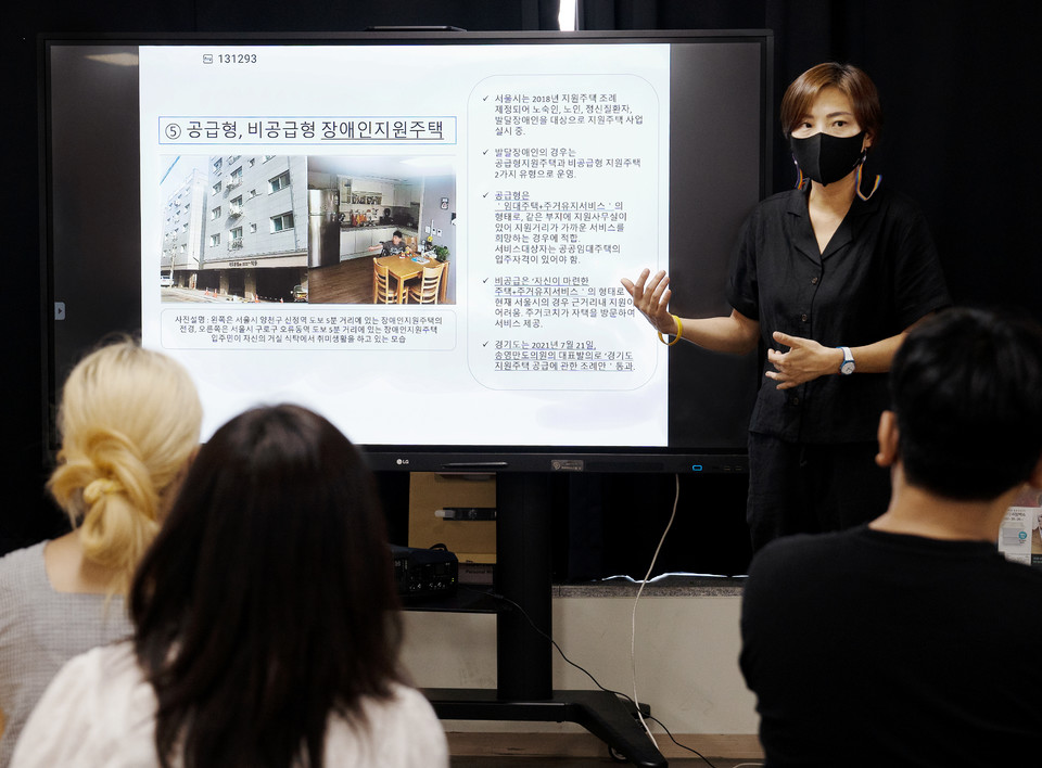 향유의집 다크투어를 온 사람들에게 향유의집 시설 폐지 과정을 설명하는 김정하 활동가. 사진에는 장애인지원주택을 알리는 내용의 PPT가 있다. 사진 현다혜