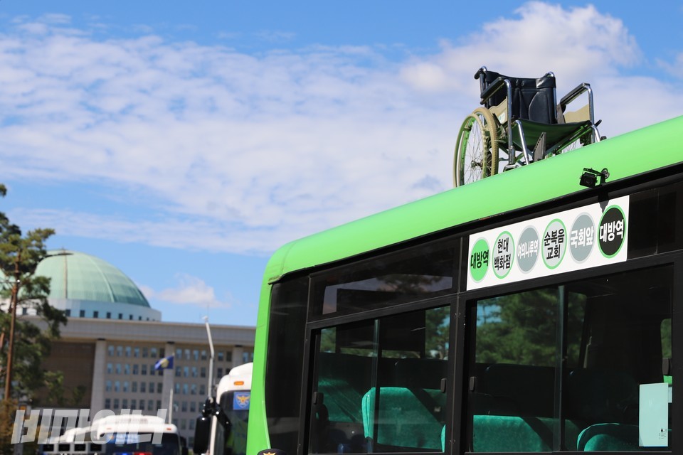 전국장애인차별철폐연대 활동가들이 지난해 9월 서울 국회의사당역 4번 출구 앞 버스정류장에서 영등포 10번 계단버스를 막아섰다. 활동가들이 버스 위로 올려 놓은 수동휠체어 뒤로 국회의사당이 보인다. 사진 이가연