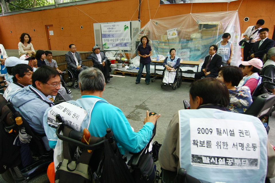 2009년 6월 15일, 석암베데스다요양원에서 나온 사람들이 서울시에 탈시설지원제도를 요구하며 마로니에공원에서 농성 중이다. 가운데 일어나서 말하는 사람이 임소연 활동가. 사진 전진호