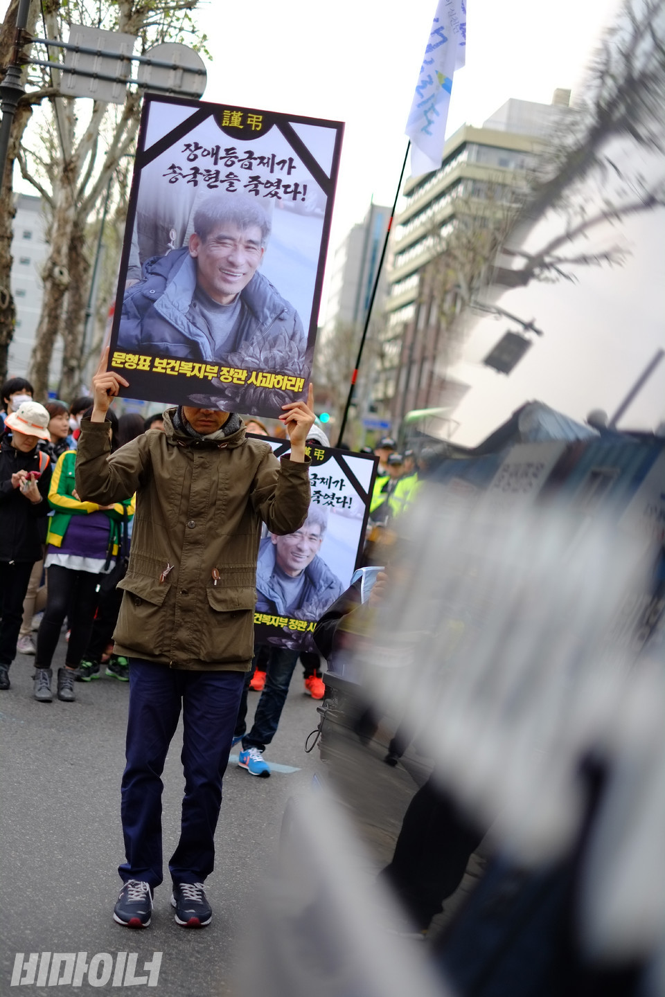 한 활동가가 도로 위에서 “장애등급제가 송국현을 죽였다! 문형표 보건복지부 장관 사과하라!”고 적힌 피켓을 들고 있다. 사진 비마이너DB