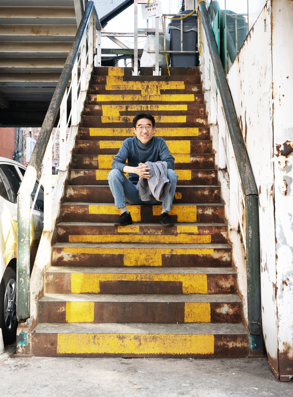 김도현 활동가가 노들야학 뒤편 계단에 앉아 있다. 계단에는 ‘노들의 꿈’이라는 글자가 노란색 글자로 크게 쓰여 있다. 사진 현다혜