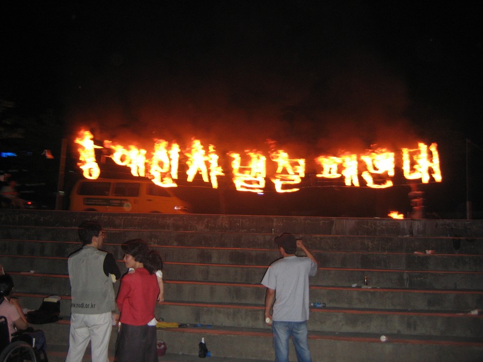 2005년 7월 14일, 장애운동활동가대회에서 전장연 강령과 규약이 통과됐다. 저녁 문화제에서 ‘장애인차별철폐연대’라는 글자가 불에 타오르고 있다. 사진 제공 김도현 
