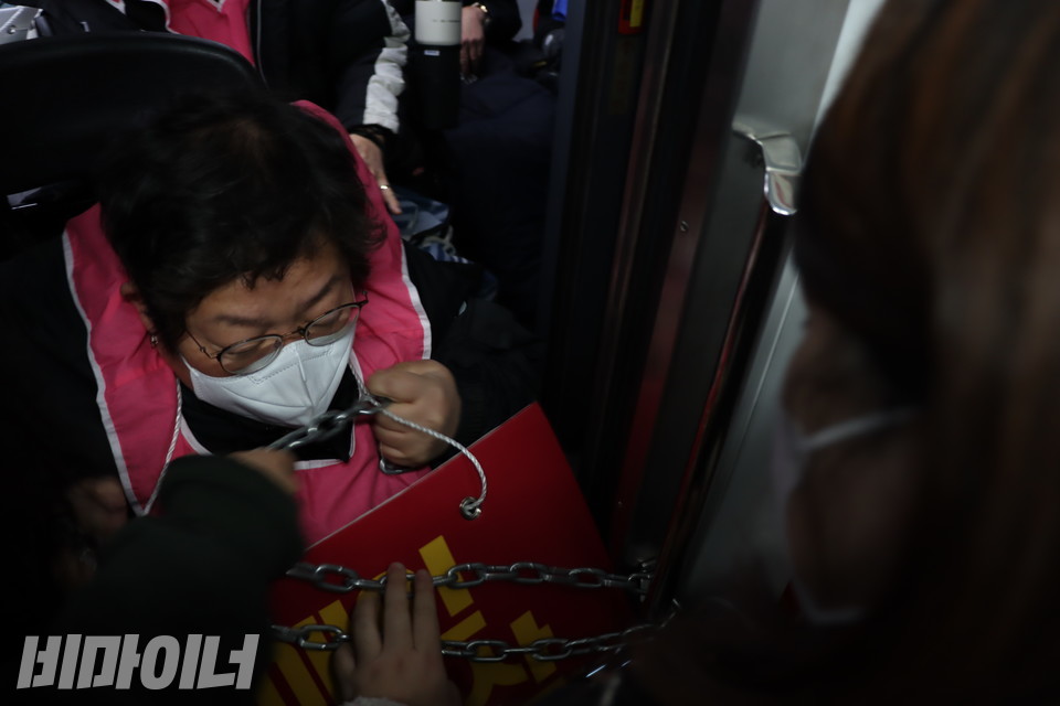 이형숙 서울시장애인자립생활센터협의회 회장이 지하철 출입구 철봉에 걸어놓은 쇠사슬을 자신의 목에 감고 있다. 사진 복건우