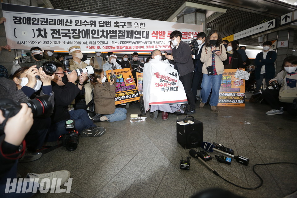 3월 30일, 1차 삭발결의식 현장. 이형숙 회장의 곱슬한 머리카락이 ‘바리캉’에 깎여 나가고 있다. 그의 뒤에는 “장애인권리예산 인수위 답변 촉구를 위한 1차 전국장애인차별철폐연대 삭발 투쟁 결의식”이라고 적힌 현수막이 걸려 있다. 사진 강혜민