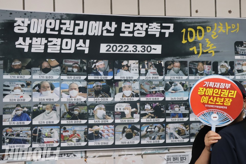 8월 30일은 삭발투쟁 100일이 되는 날이었다. 삼각지역 벽에 붙은 현수막에 ‘장애인권리예산 보장촉구 삭발결의식 2022.3.30~ 100일차의 기록’이라는 문구가 적혀 있다. 문구 아래에 삭발 투쟁 참여자들의 사진과 이름이 나열돼 있다. 사진 하민지