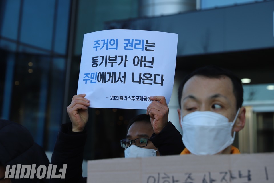 이동현 홈리스행동 상임활동가가 ‘주거의 권리는 등기부가 아닌 주민에게서 나온다’라고 적힌 피켓을 들고 있다. 사진 하민지