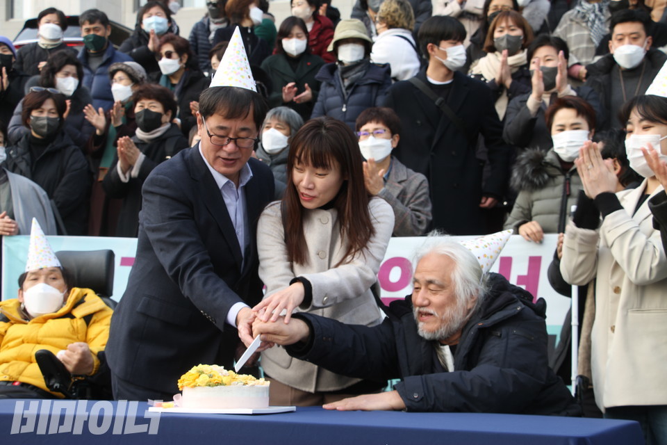기자회견 참가자들이 국회 본청 계단 앞에서 “기쁘다 CRPD 선택의정서 14년 만에 오셨네”라는 문구가 적힌 케이크 커팅식을 하고 있다. 사진 한국장애포럼 
