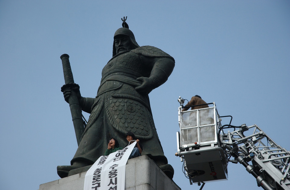 경찰이 소방 차량을 타고 이순신 동상에 접근하는 가운데, 송효정 활동가가 구호를 외치고 있다. 사진 n_m 