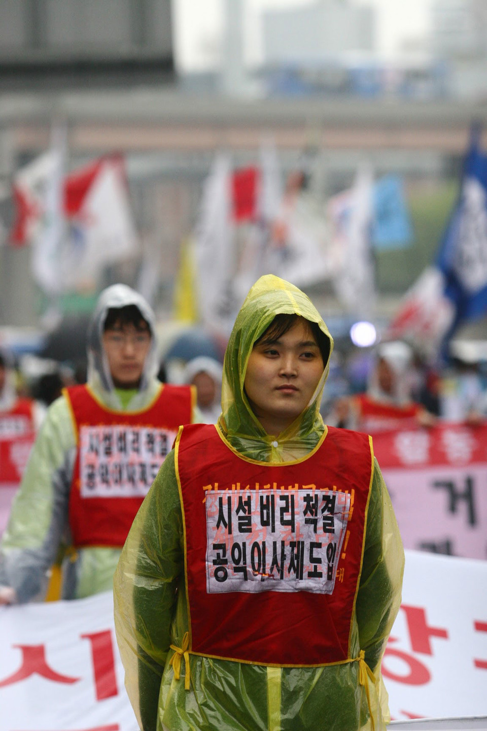 2007년 4월 20일 장애인차별철폐의 날에 송효정 활동가가 우비를 입고 행진하고 있다. 그가 입은 몸피씨에는 ‘시설 비리 척결 공익이사제 도입’이 적혀 있다. 사진 전진호 